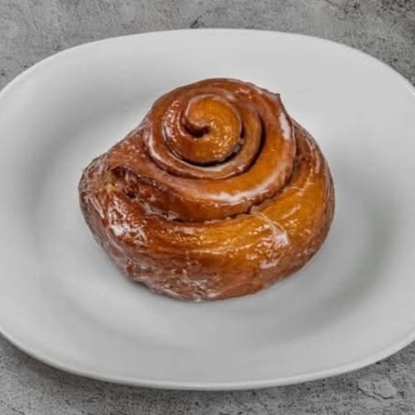Dat Donut's glazed cinnamon roll on a white plate.