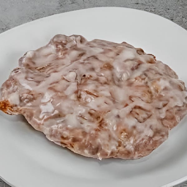 A glazed apple fritter from Dat Donut on a white plate.