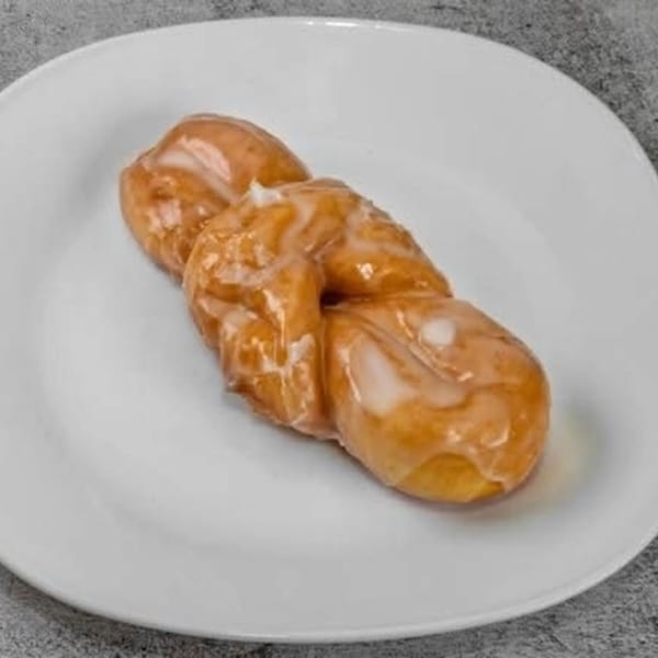 A glazed Dat Donut twist pastry on a white plate.